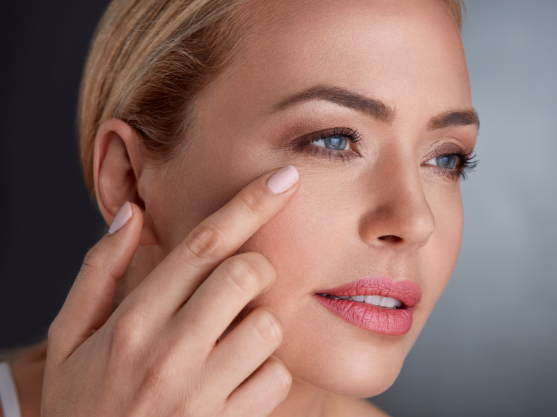 Woman touching her face, showcasing results of Ultherapy skin tightening treatment, enhancing firmness and reducing wrinkles.